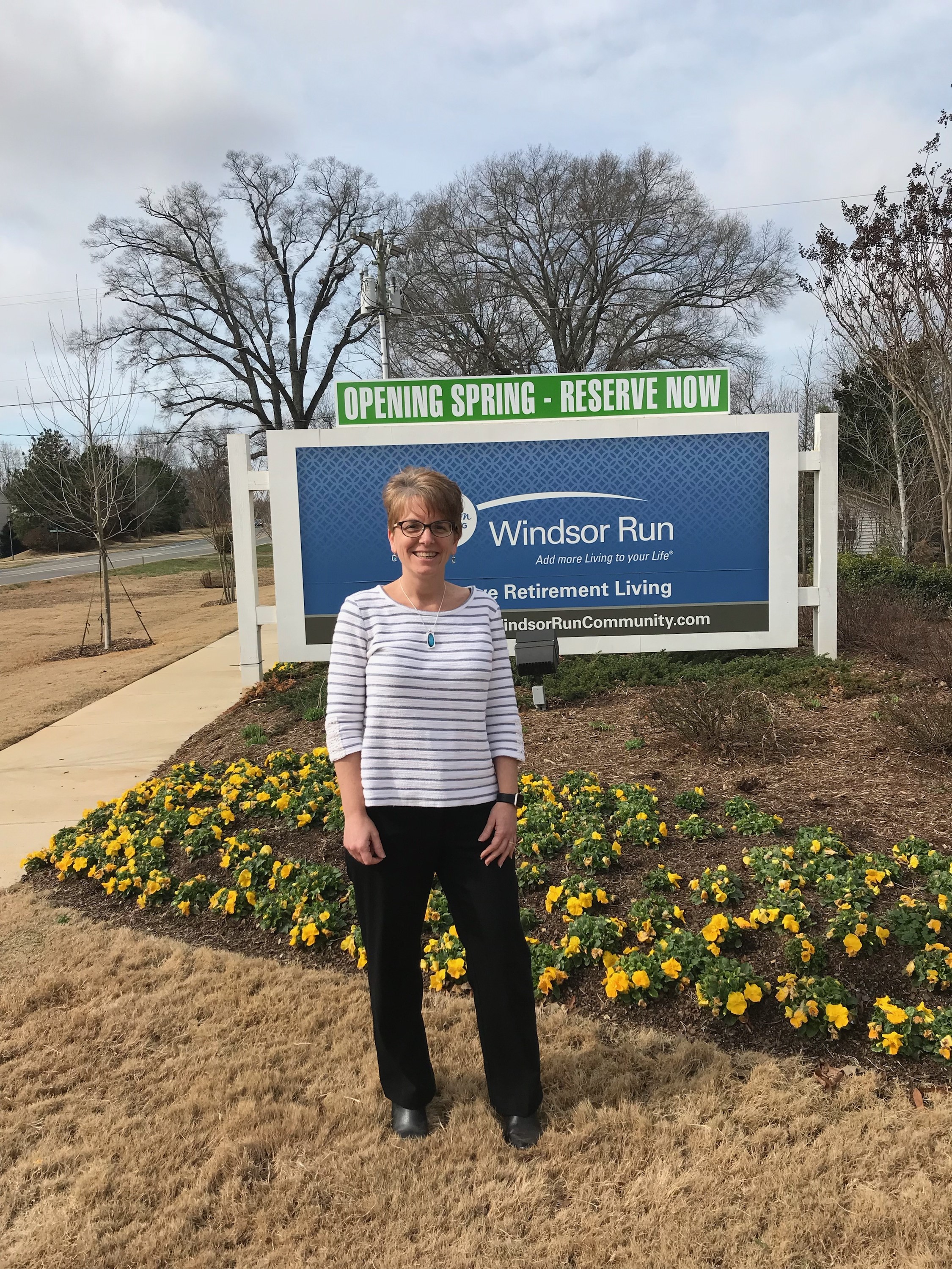 Karen Kollmer, project manager at Windsor Run, stands in front of the campus sign on the McKee Road entrance.