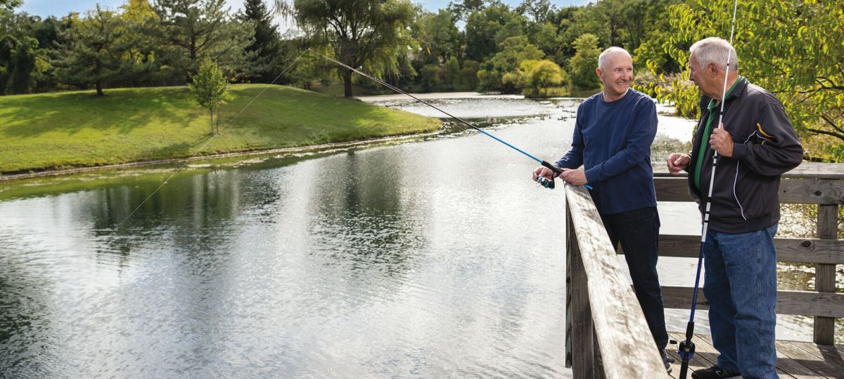 Two men enjoying a peaceful day fishing at the pond in our senior living community.